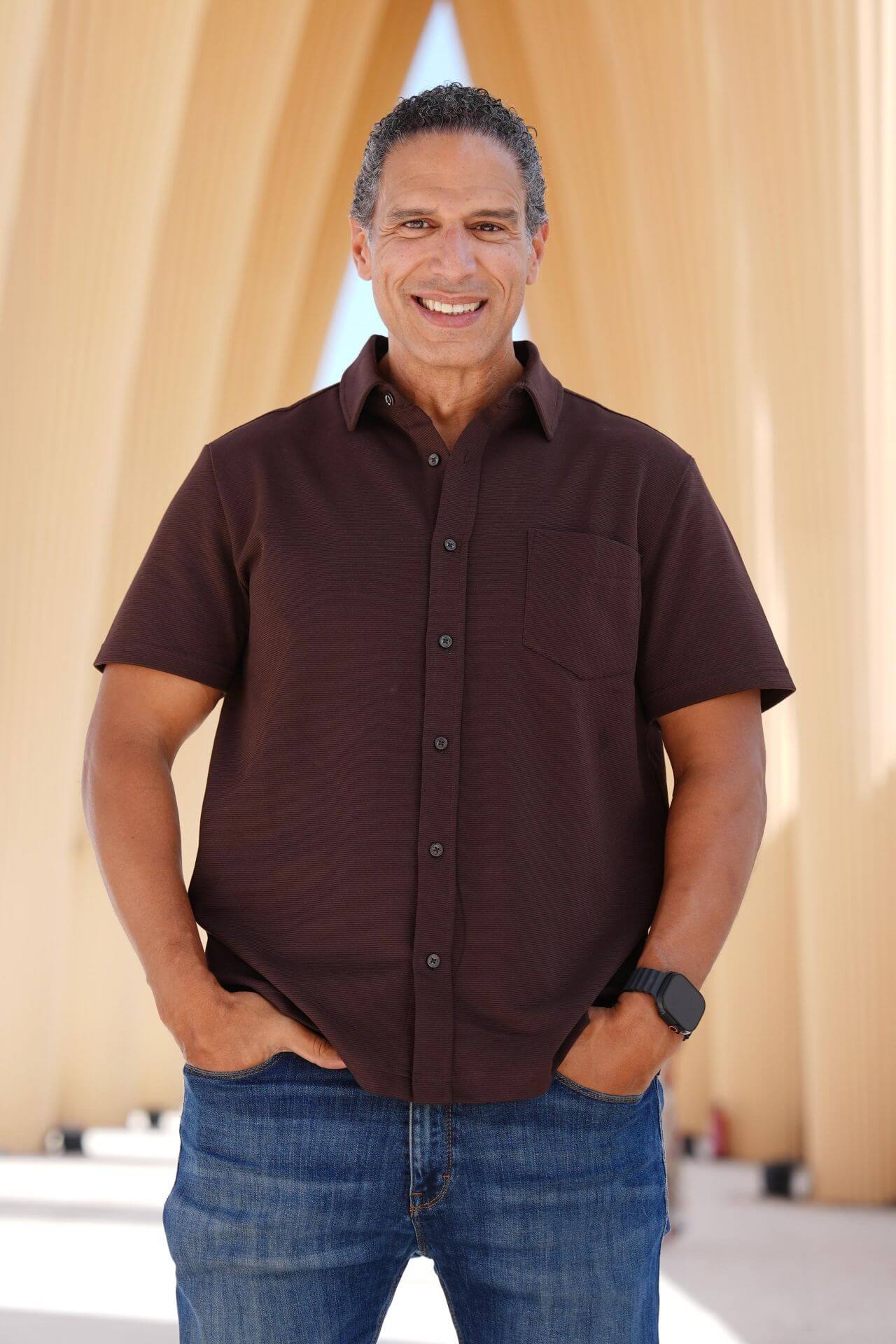A casual portrait of Mohamed Amer, smiling, standing inside a modern, sunlit architectural structure in El Gouna.